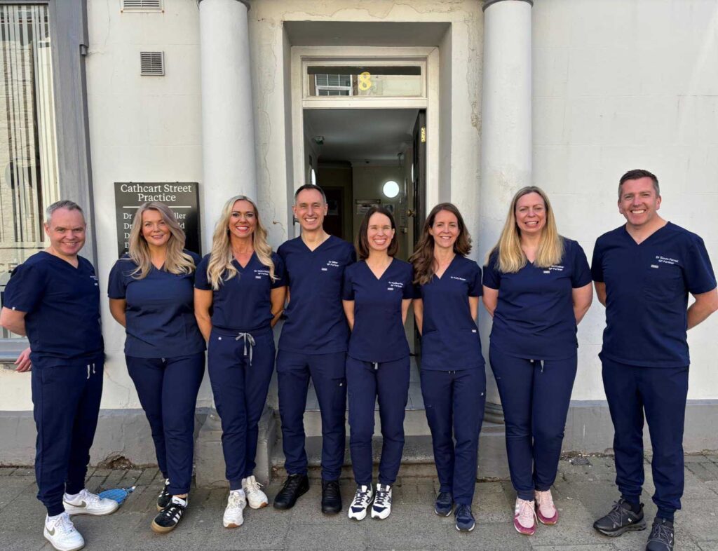 Team of GPs standing in front of surgery entrance